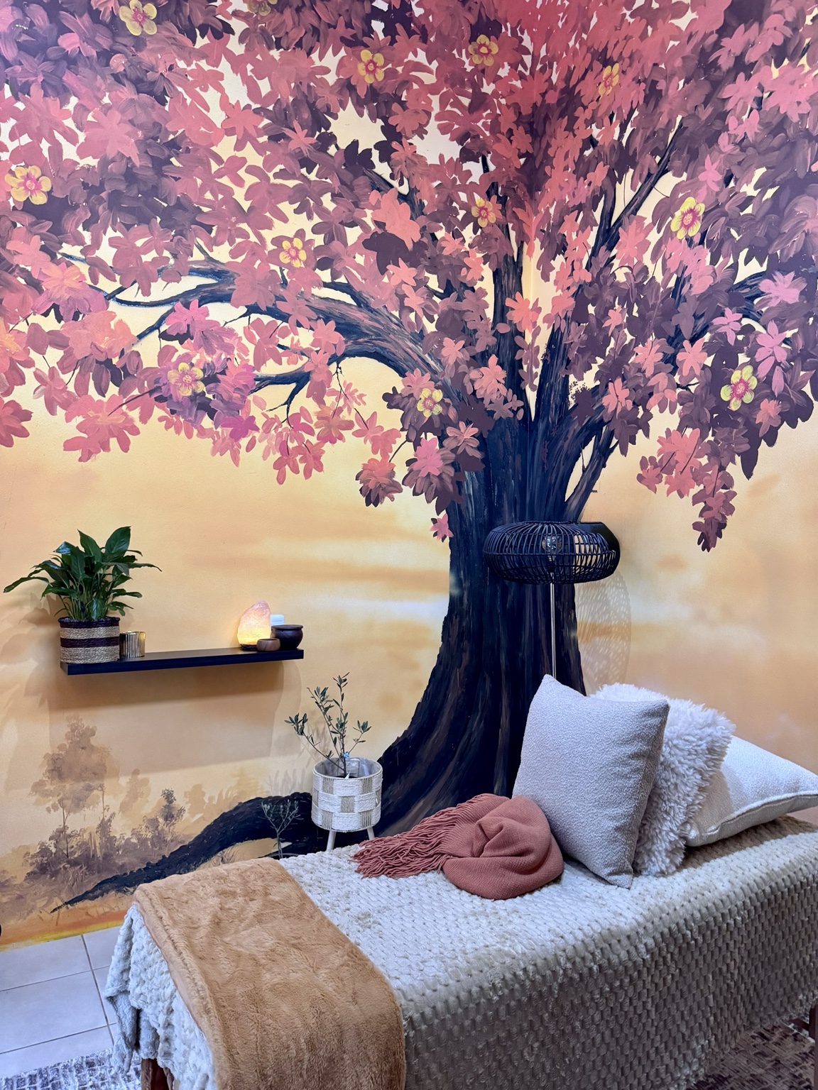 The Roots and Radiance treatment room from another angle, showing the Tree of Life mural and treatment bed